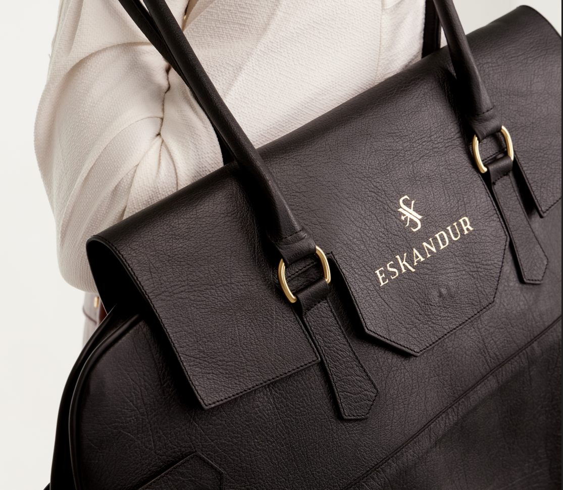 Man holding a black leather Eskandur garment bag